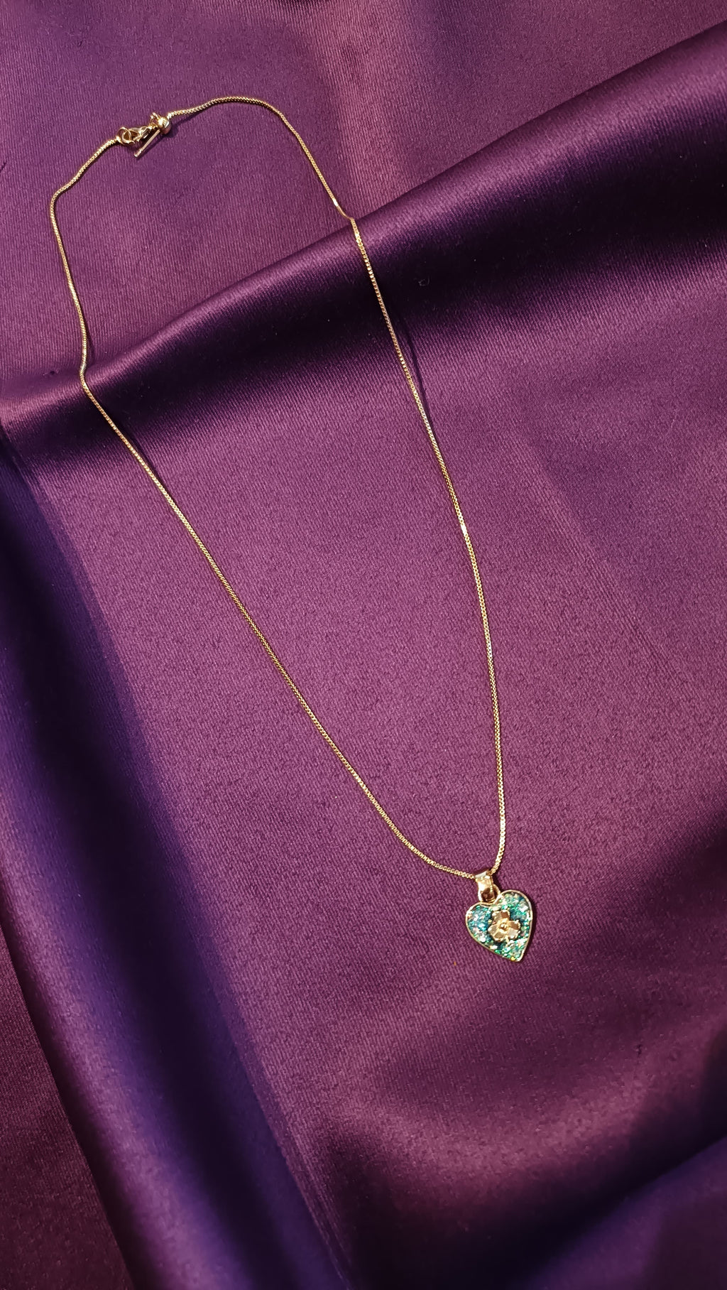 Gold Emerald Pavé Heart Pendant Box Chain Necklace full length flat lay on purple fabric showing lobster clasp and extender