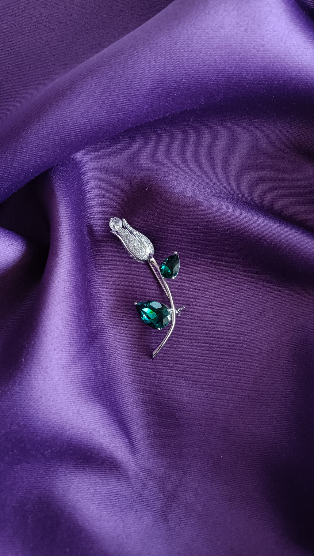 Silver Emerald Crystal Tulip Bud & Leaf Lapel Brooch Pin front view flat lay on purple fabric showing emerald crystals and pavé tulip bud