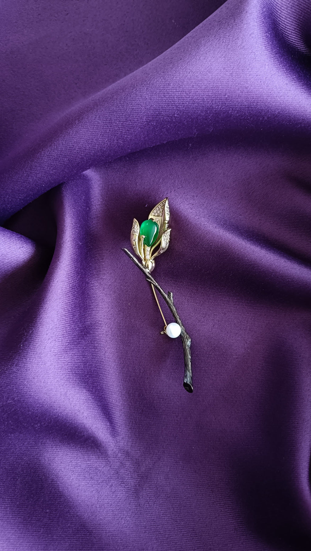 Gold Green Onyx Cabochon & Pavé Leaf Tulip Bud Long Stem Lapel Brooch Pin front view flat lay on purple fabric showing green onyx cabochon, pavé leaves and pearl drop