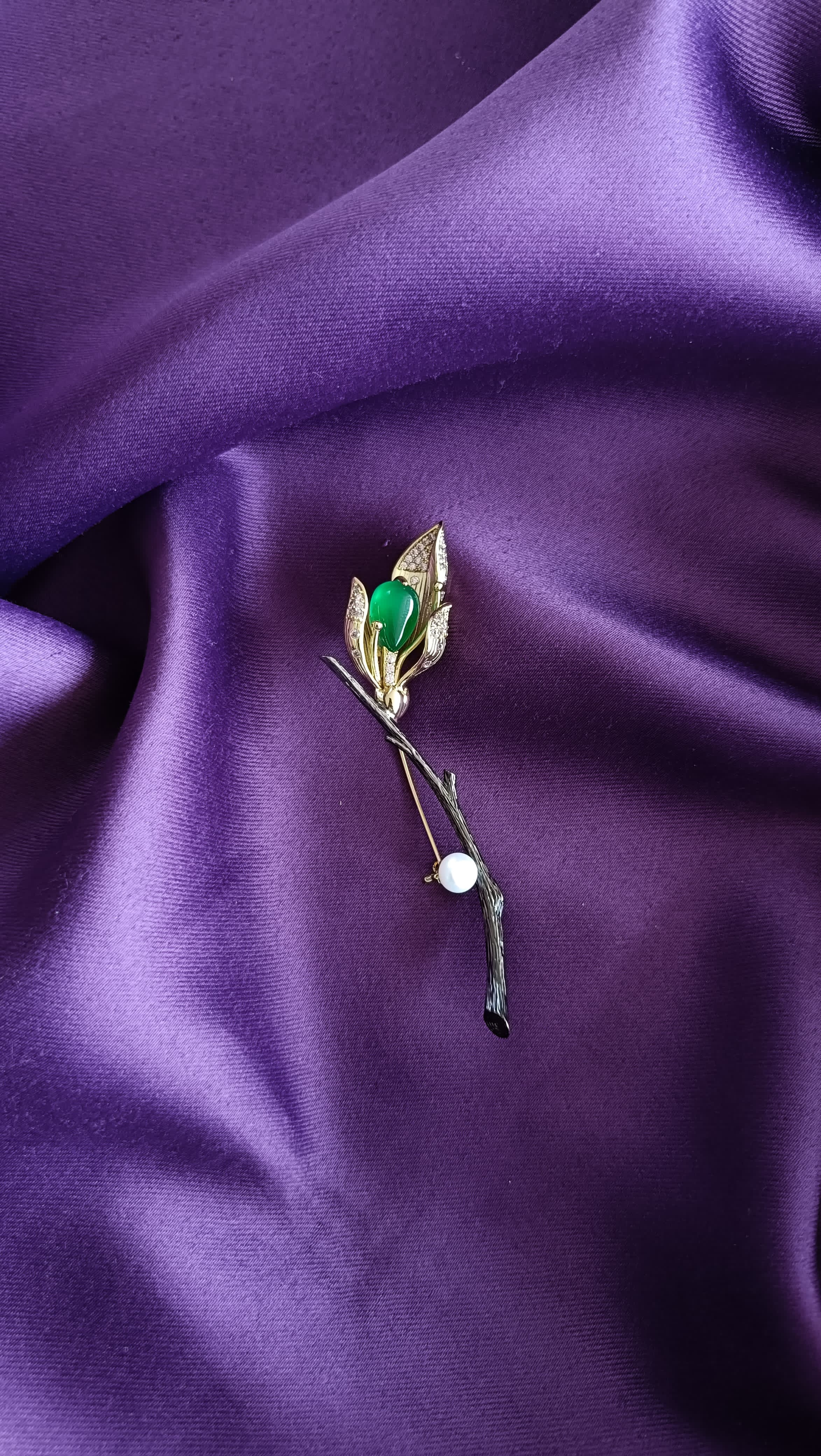 Gold Green Onyx Cabochon & Pavé Leaf Tulip Bud Long Stem Lapel Brooch Pin front view flat lay on purple fabric showing green onyx cabochon, pavé leaves and pearl drop