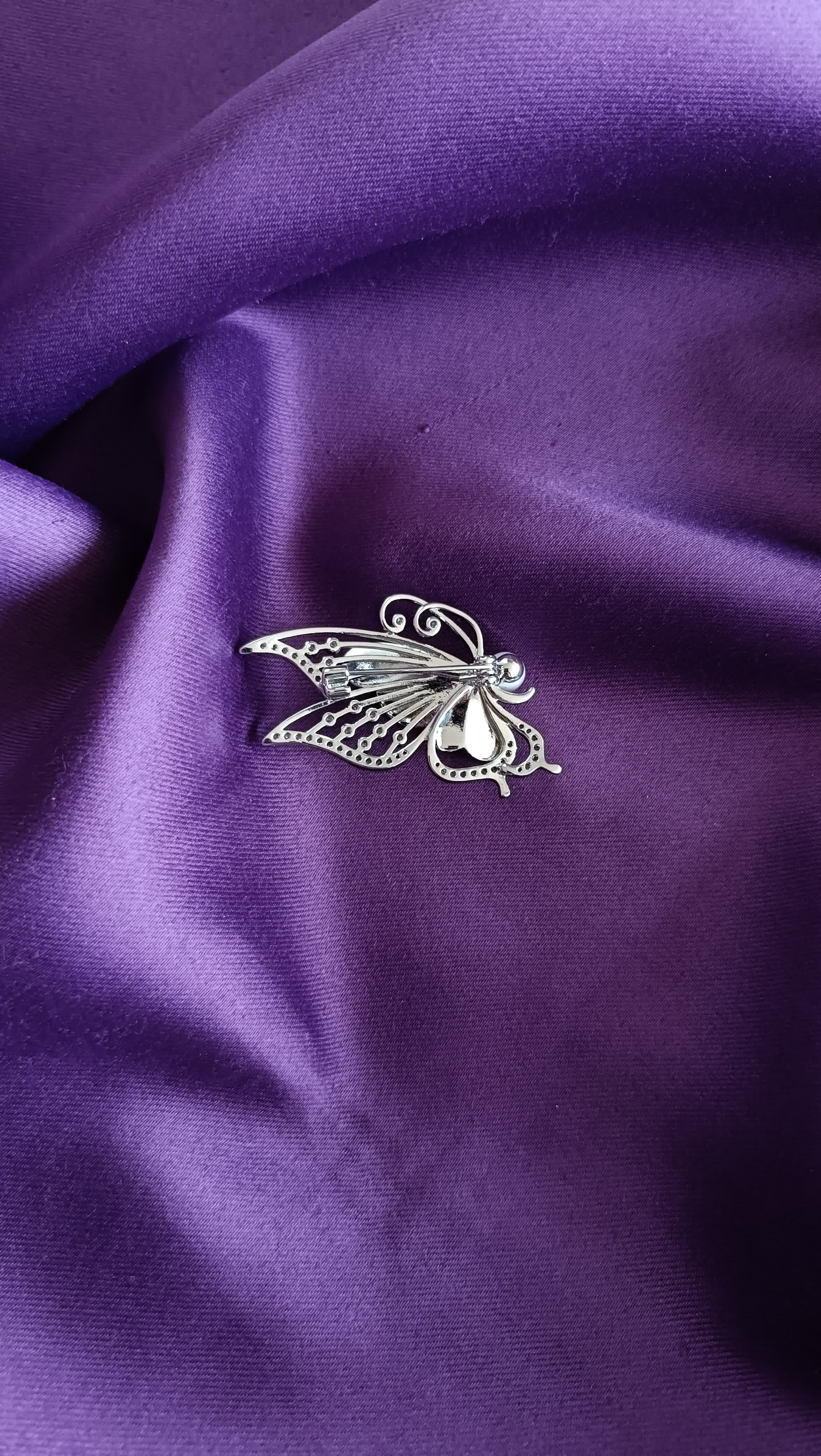 Silver Teal Pavé & White Crystal Butterfly Lapel Brooch Pin with Pearl Body reverse side flat lay on purple fabric showing silver filigree lower wing and pin back closure