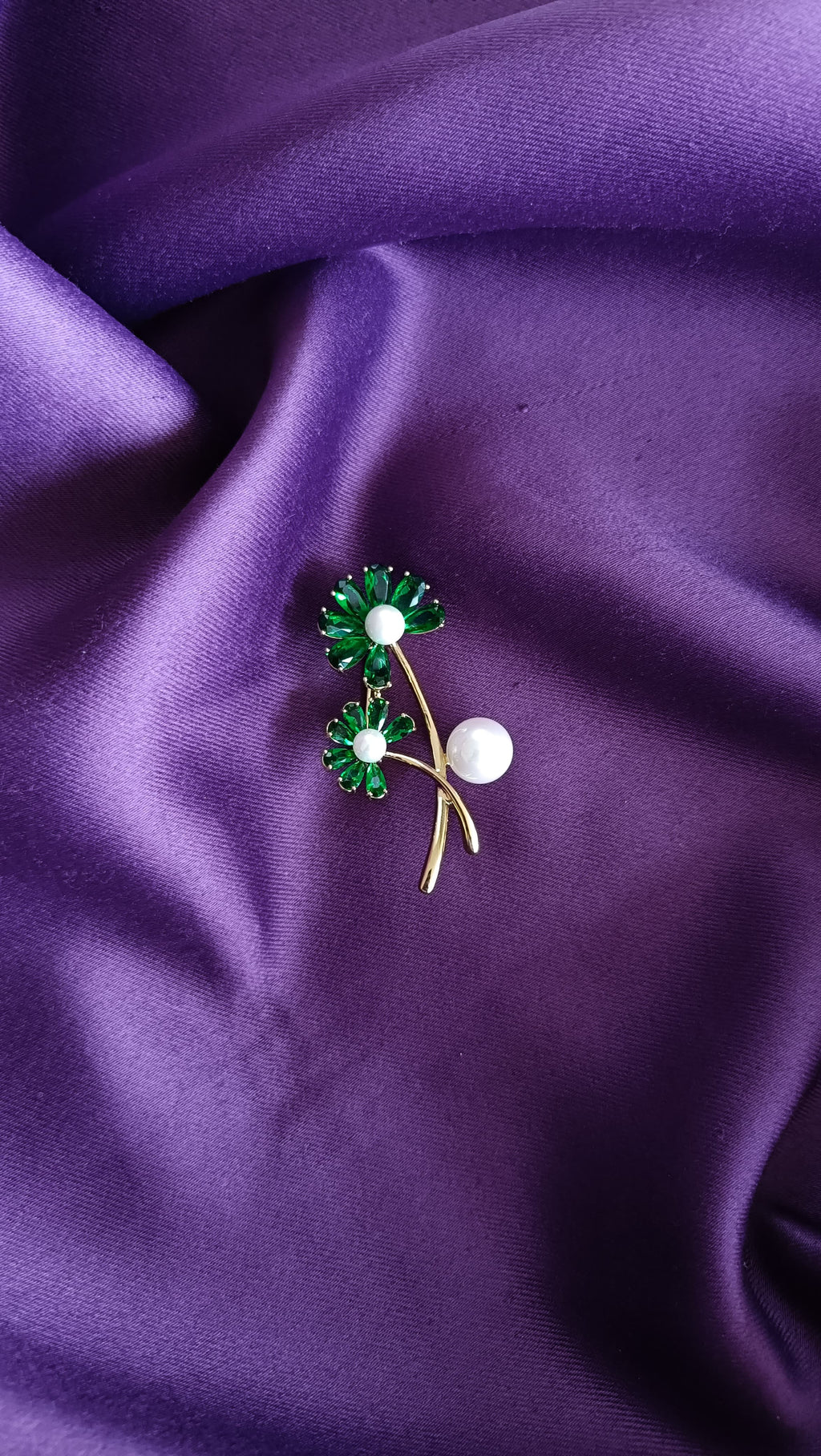 Gold Emerald Crystal Daisy Double Bloom & Pearl Lapel Brooch Pin front view flat lay on purple fabric showing emerald crystal petals, pearl centres and forked stem pearl