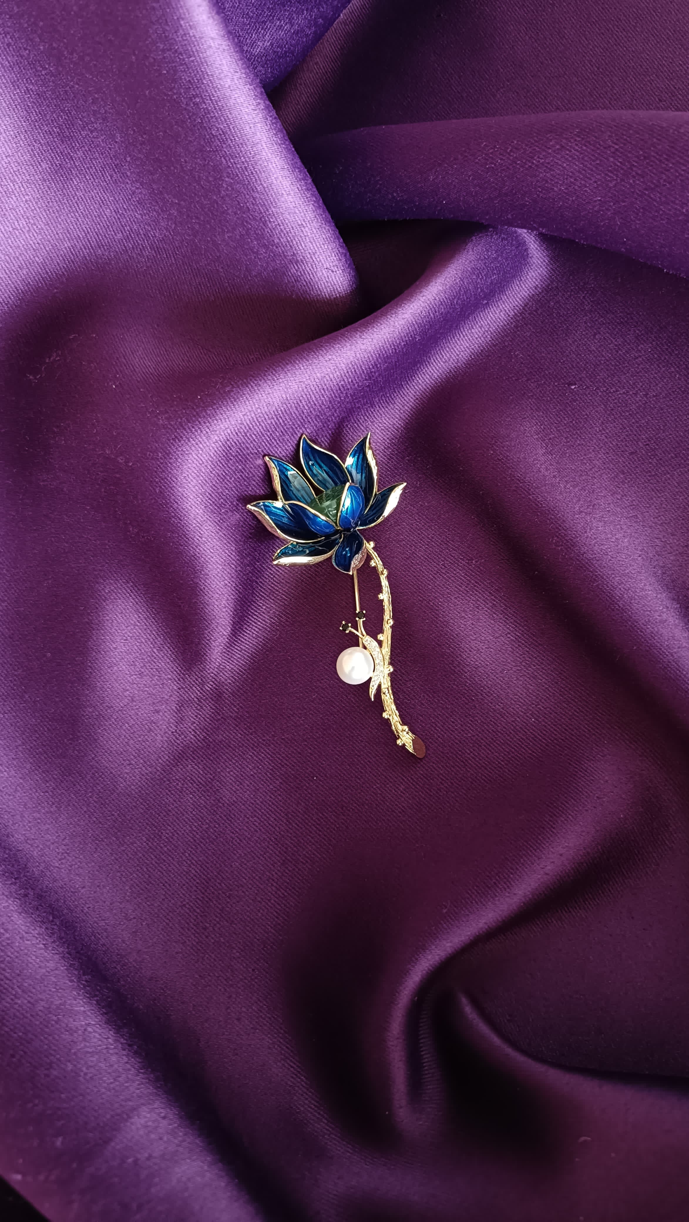 Gold Deep Blue Enamel Lotus Bloom Long Stem Lapel Brooch Pin front view flat lay on purple fabric showing cobalt blue enamel petals, teal centre and pearl on gold twig stem