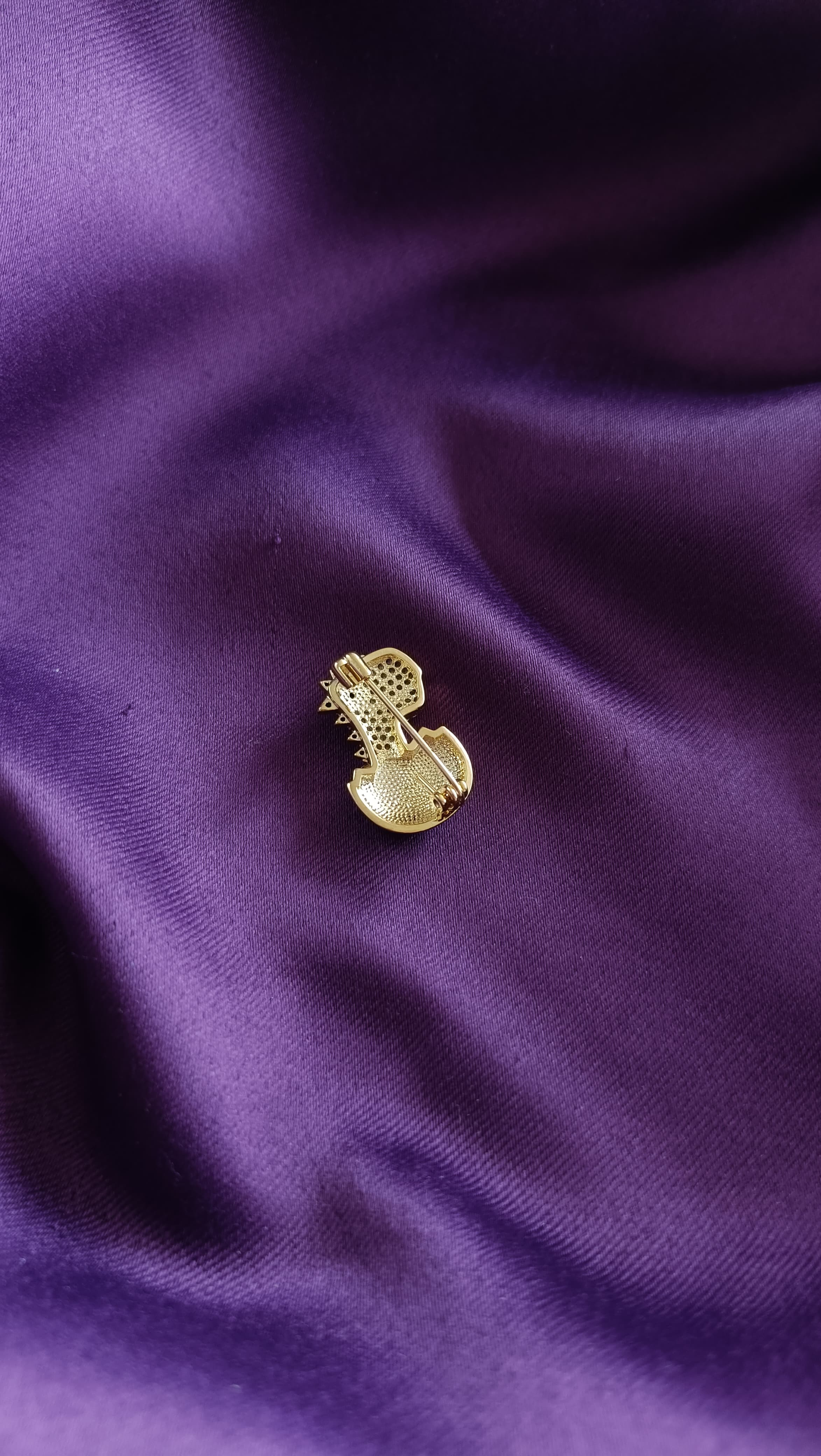 Gold Pavé Baby Dinosaur Hatching from Egg Lapel Brooch Pin reverse side flat lay on purple fabric showing gold egg body and pin back closure