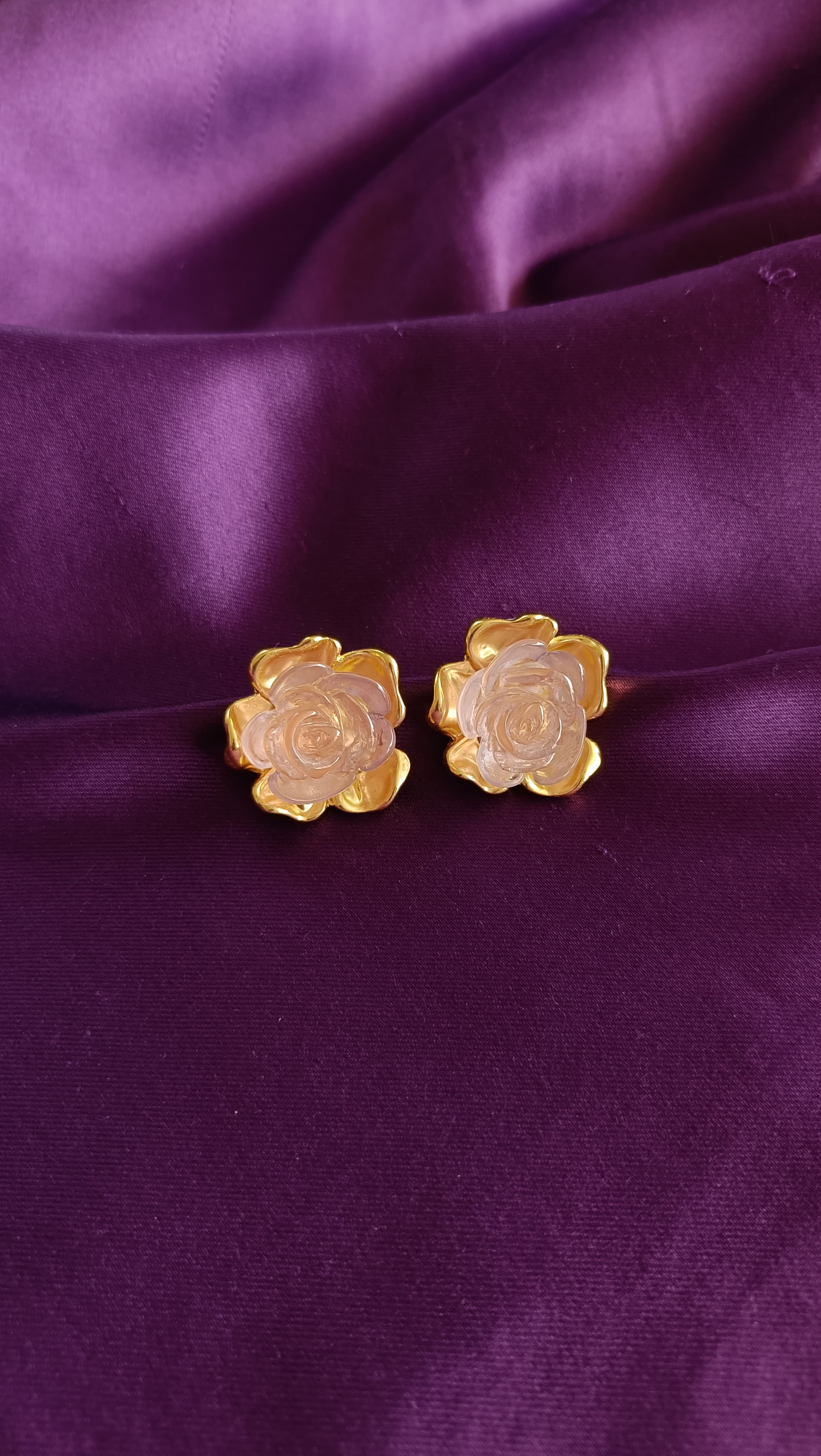 Gold Rose Quartz Carved Rose Stud Earrings pair flat lay on purple fabric