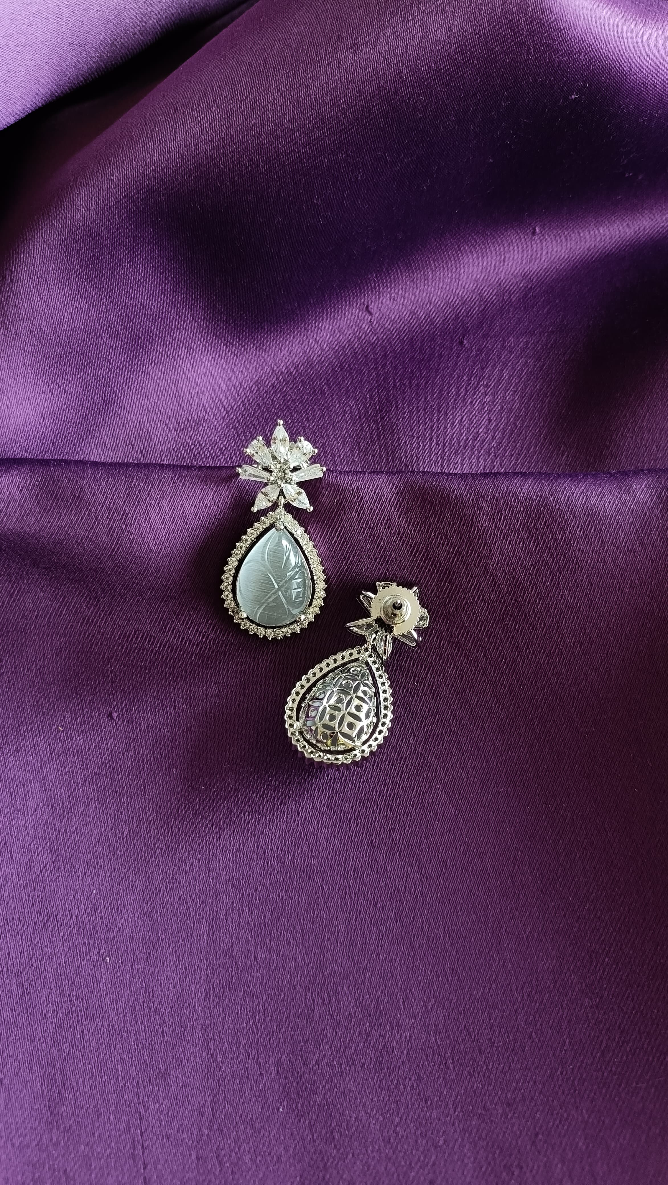 Silver Carved Jade Pear-Drop & Marquise Crystal Flower Drop Earrings front and back flat lay on purple fabric
