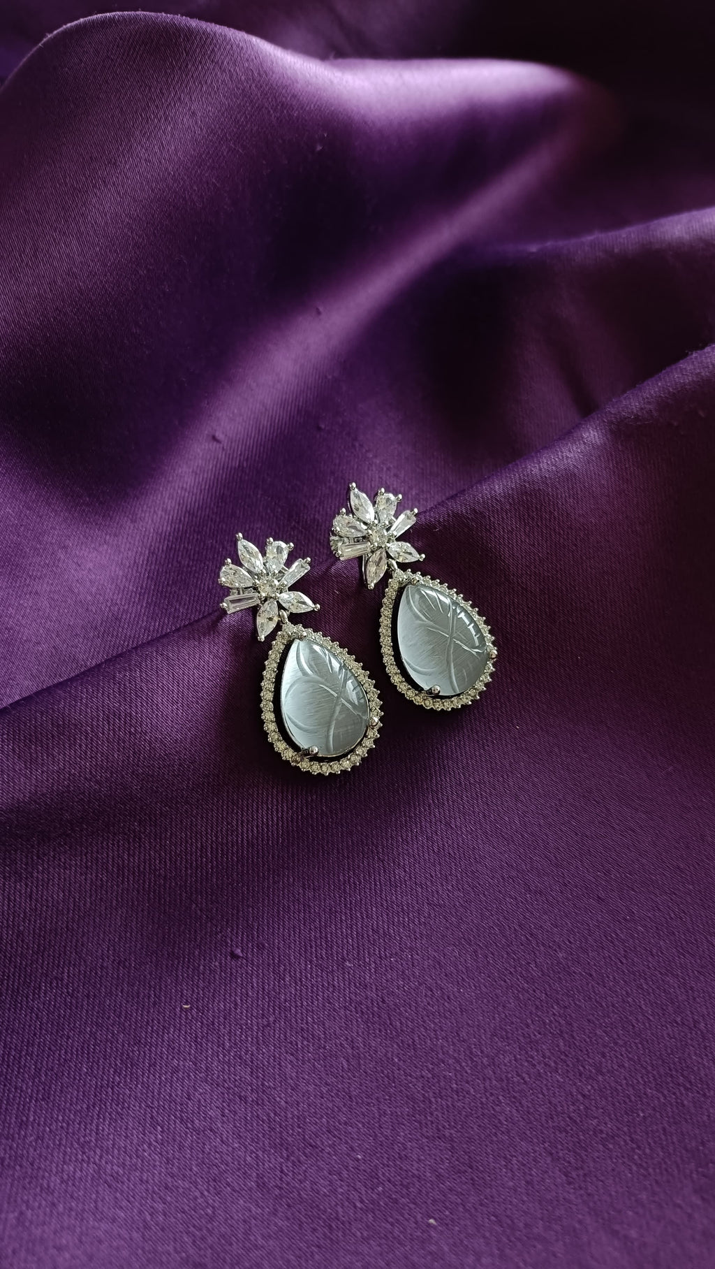 Silver Carved Jade Pear-Drop & Marquise Crystal Flower Drop Earrings pair flat lay on purple fabric
