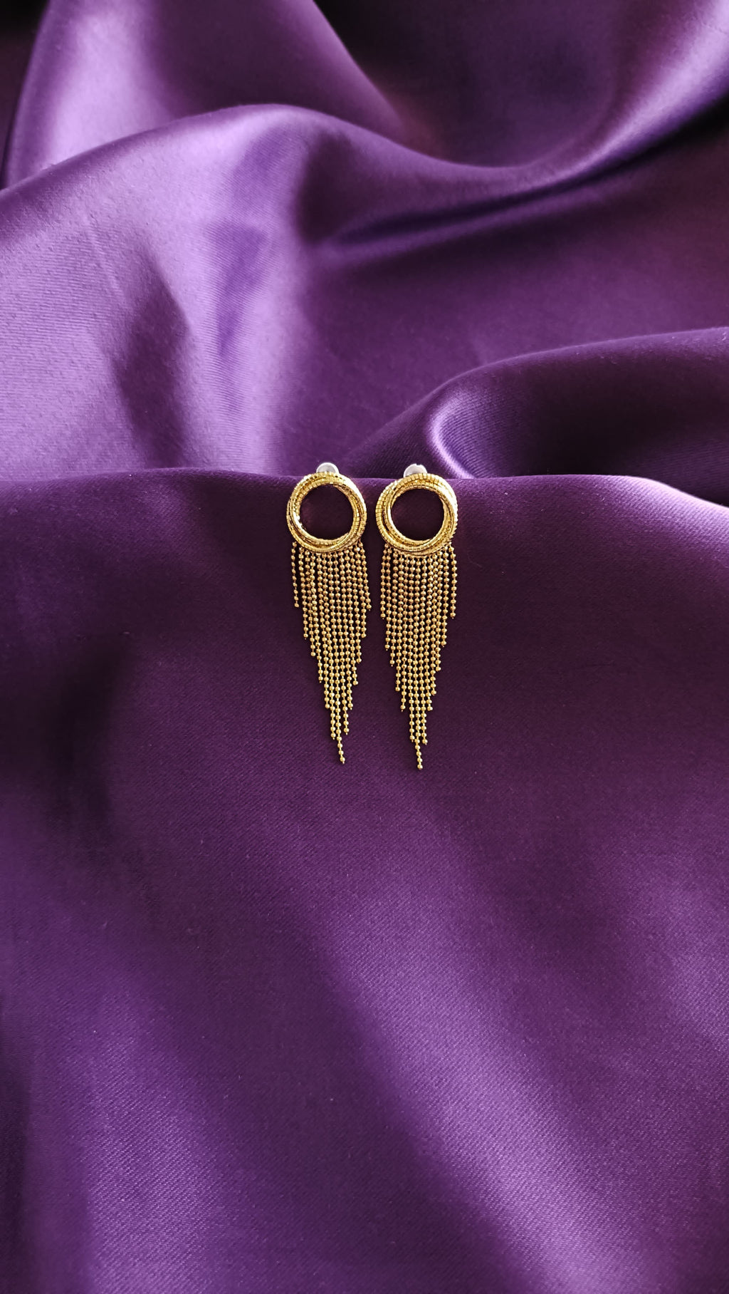 Gold Textured Open Circle Ball Chain Fringe Tassel Earrings pair flat lay on purple fabric
