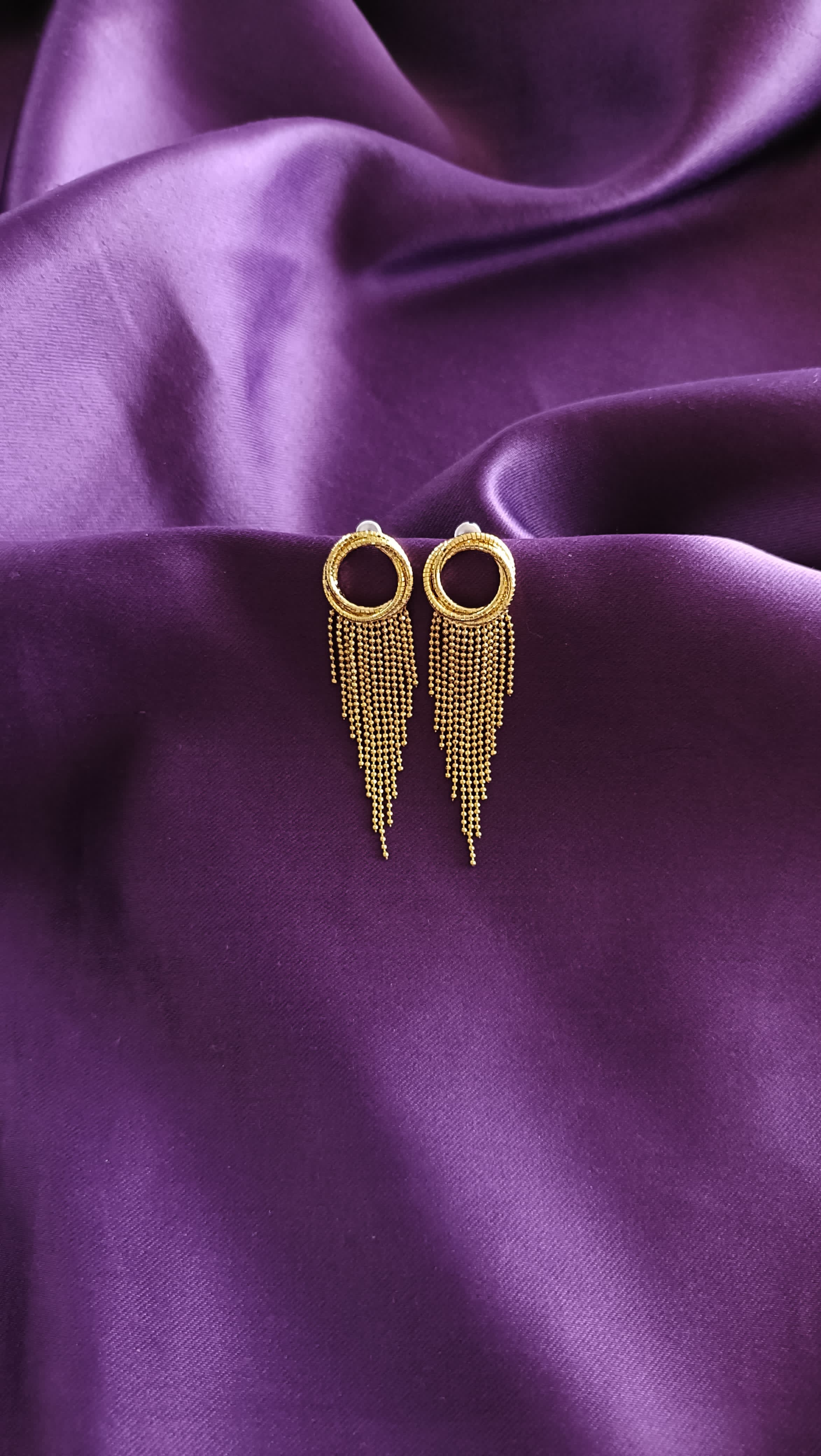 Gold Textured Open Circle Ball Chain Fringe Tassel Earrings pair flat lay on purple fabric