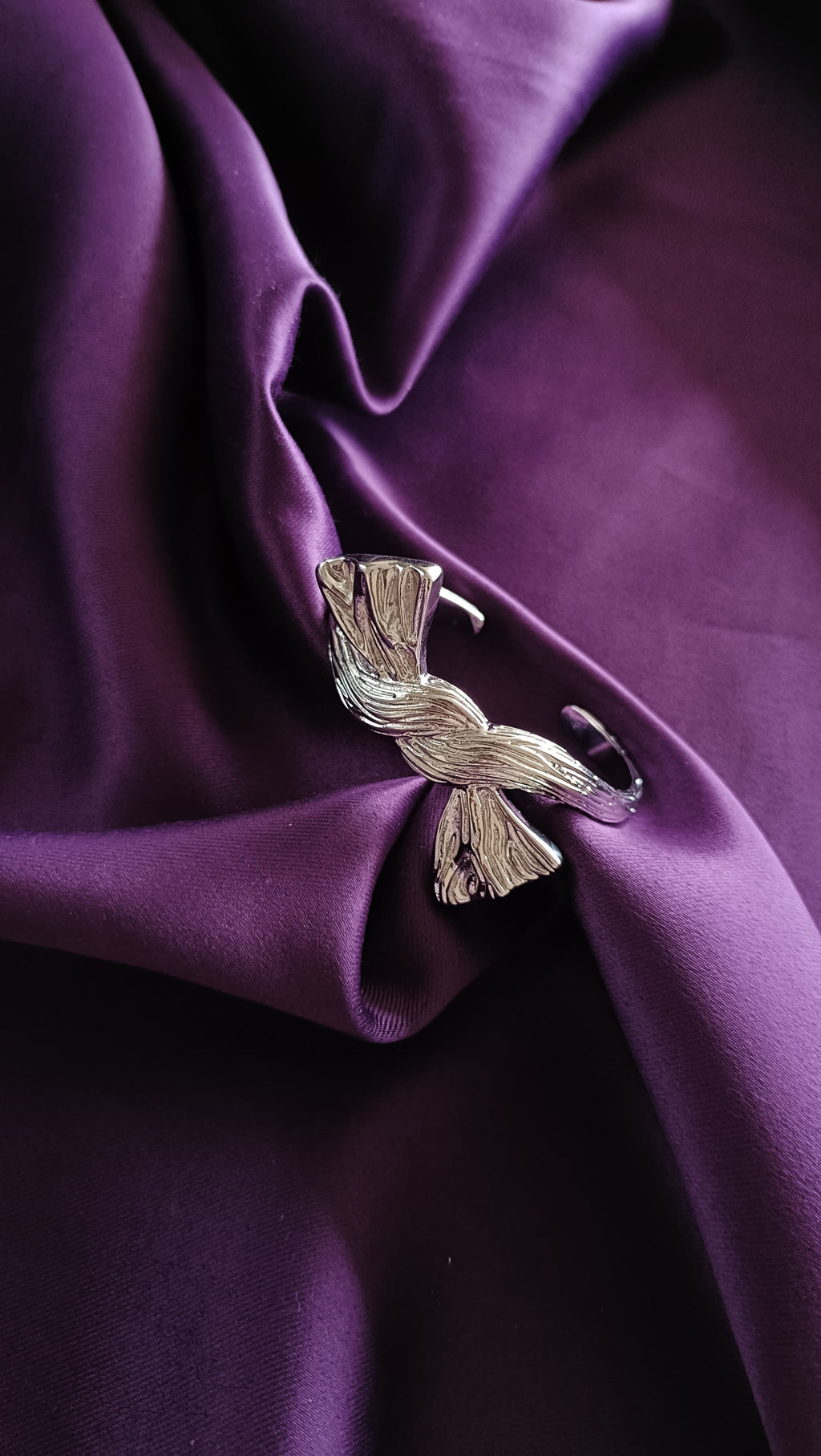 Silver Textured Ribbon Bow Cuff Bracelet open cuff flat lay on purple fabric
