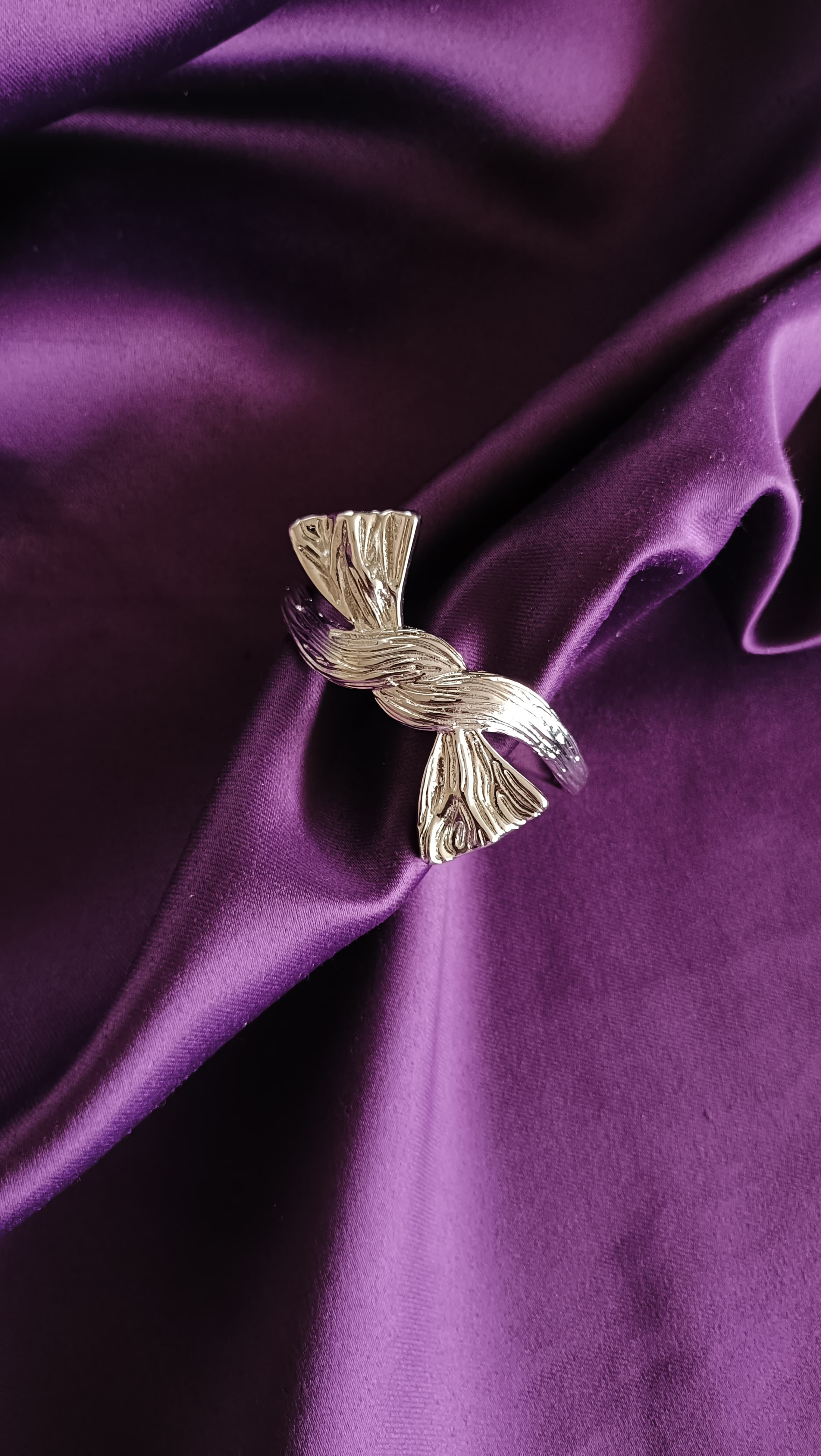 Silver Textured Ribbon Bow Cuff Bracelet top view flat lay on purple fabric