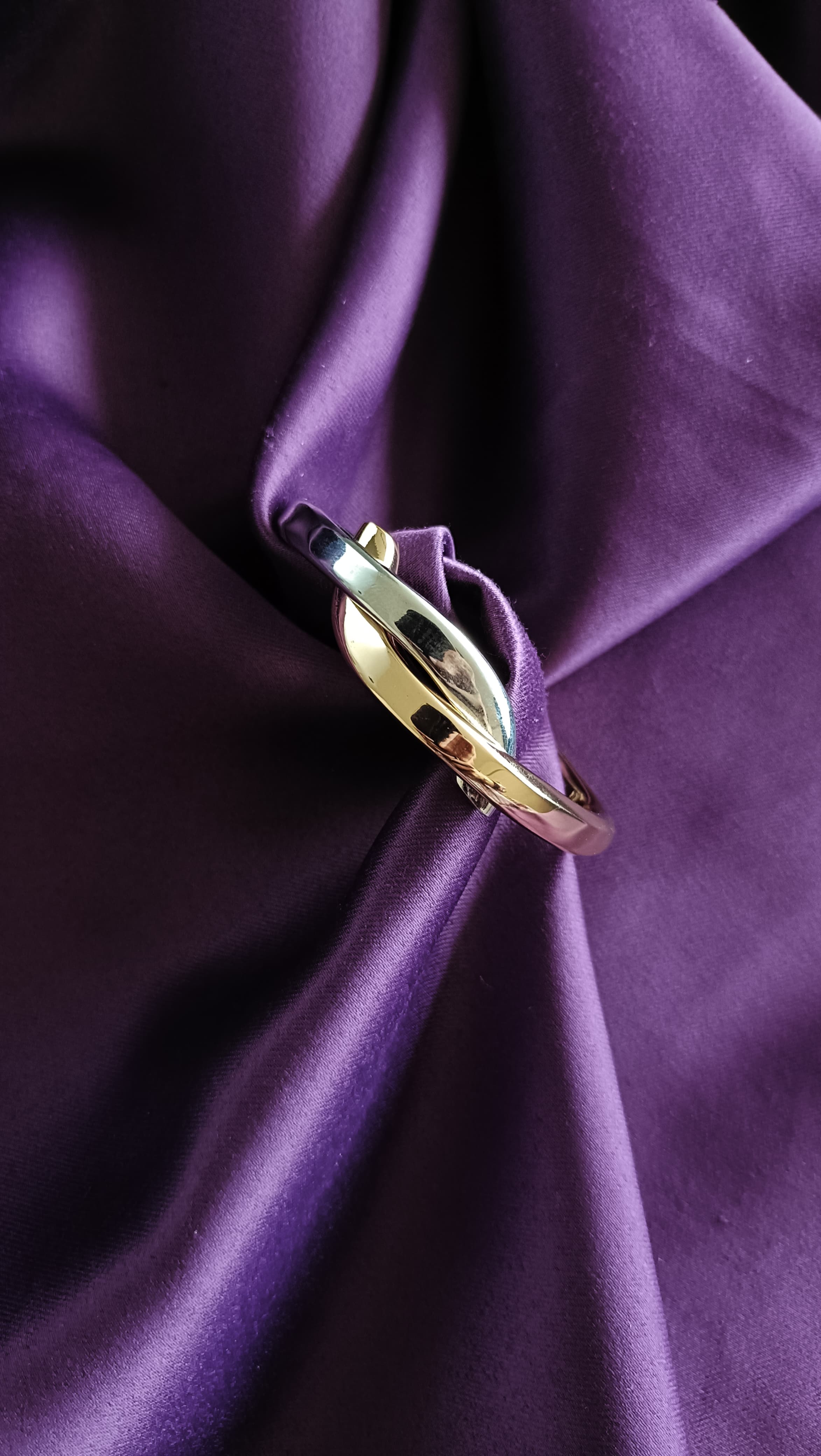 Bi-Tone Interlocking Oval Bangle Set gold-side flat lay on purple fabric
