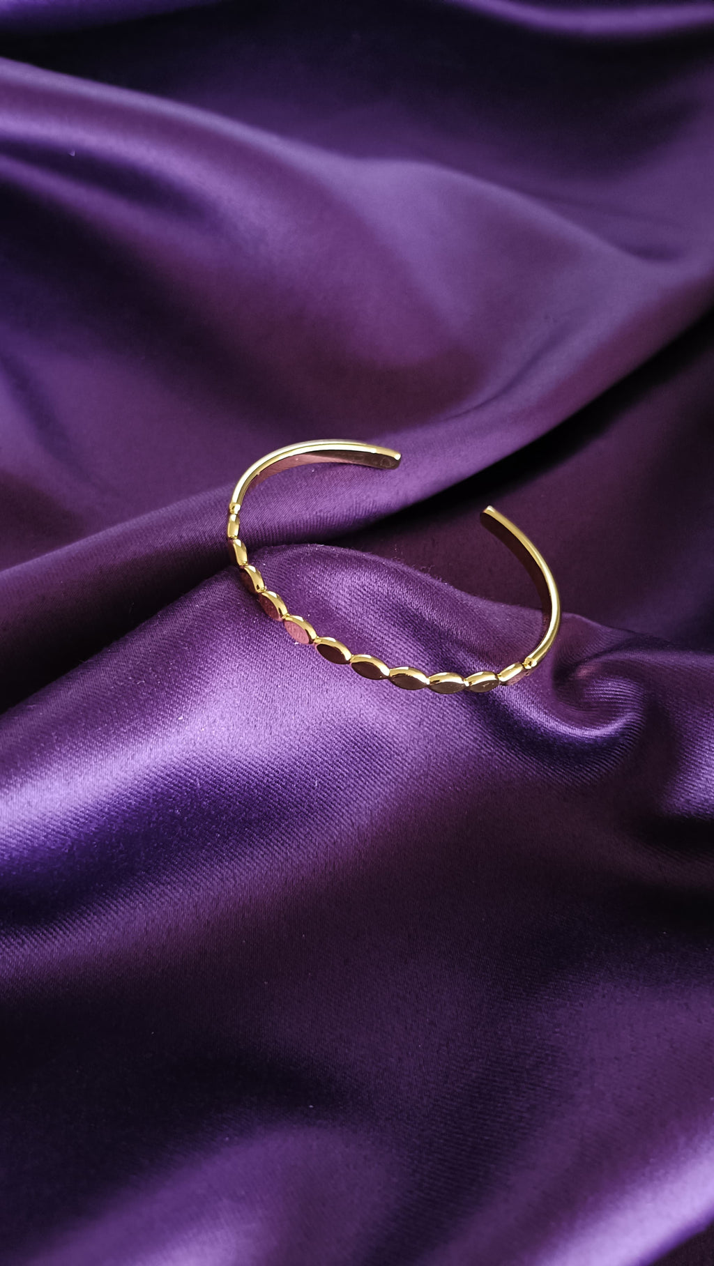 Gold Oval Disc Station Open Cuff Bracelet open cuff flat lay on purple fabric