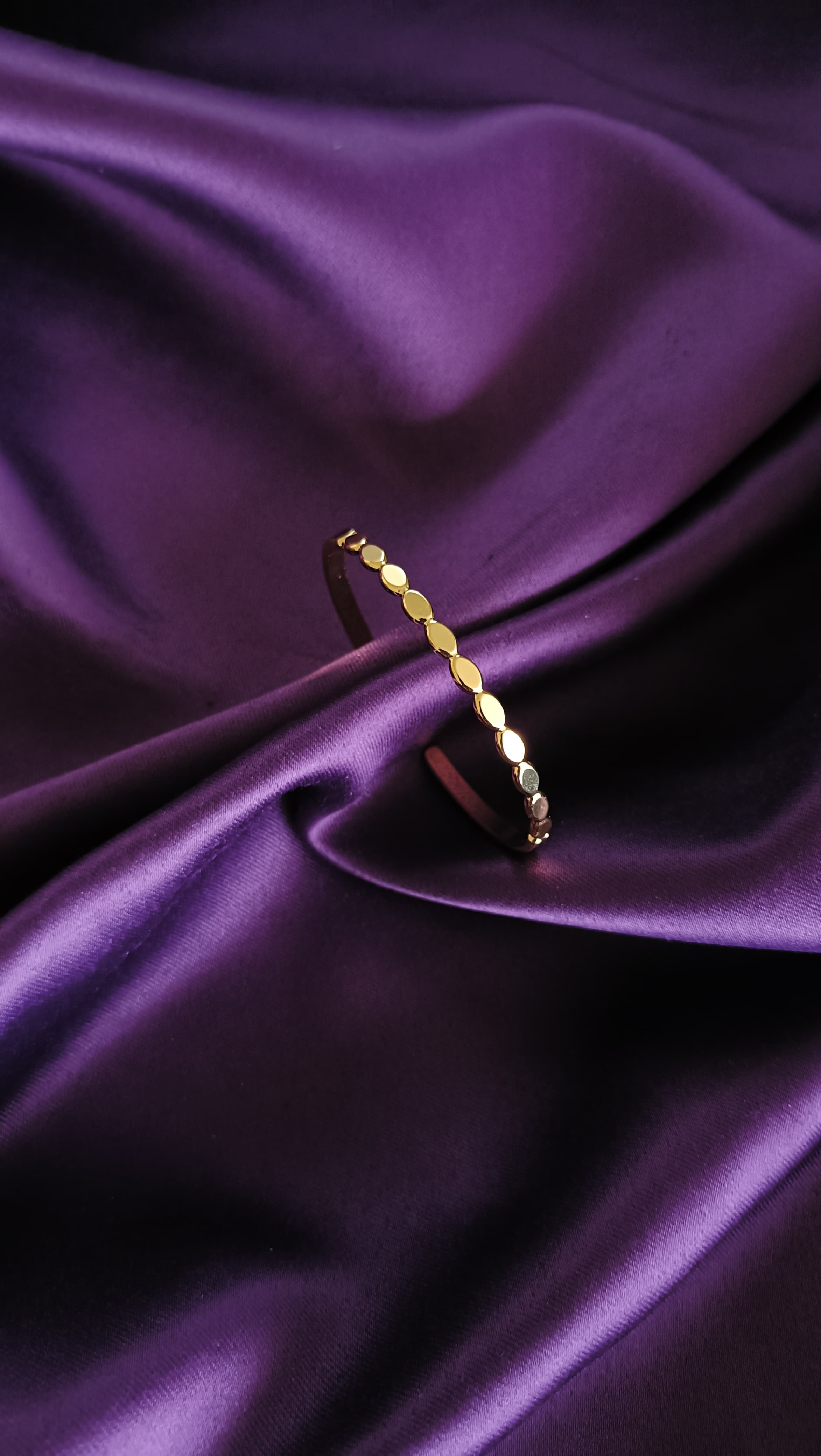 Gold Oval Disc Station Open Cuff Bracelet upright flat lay on purple fabric