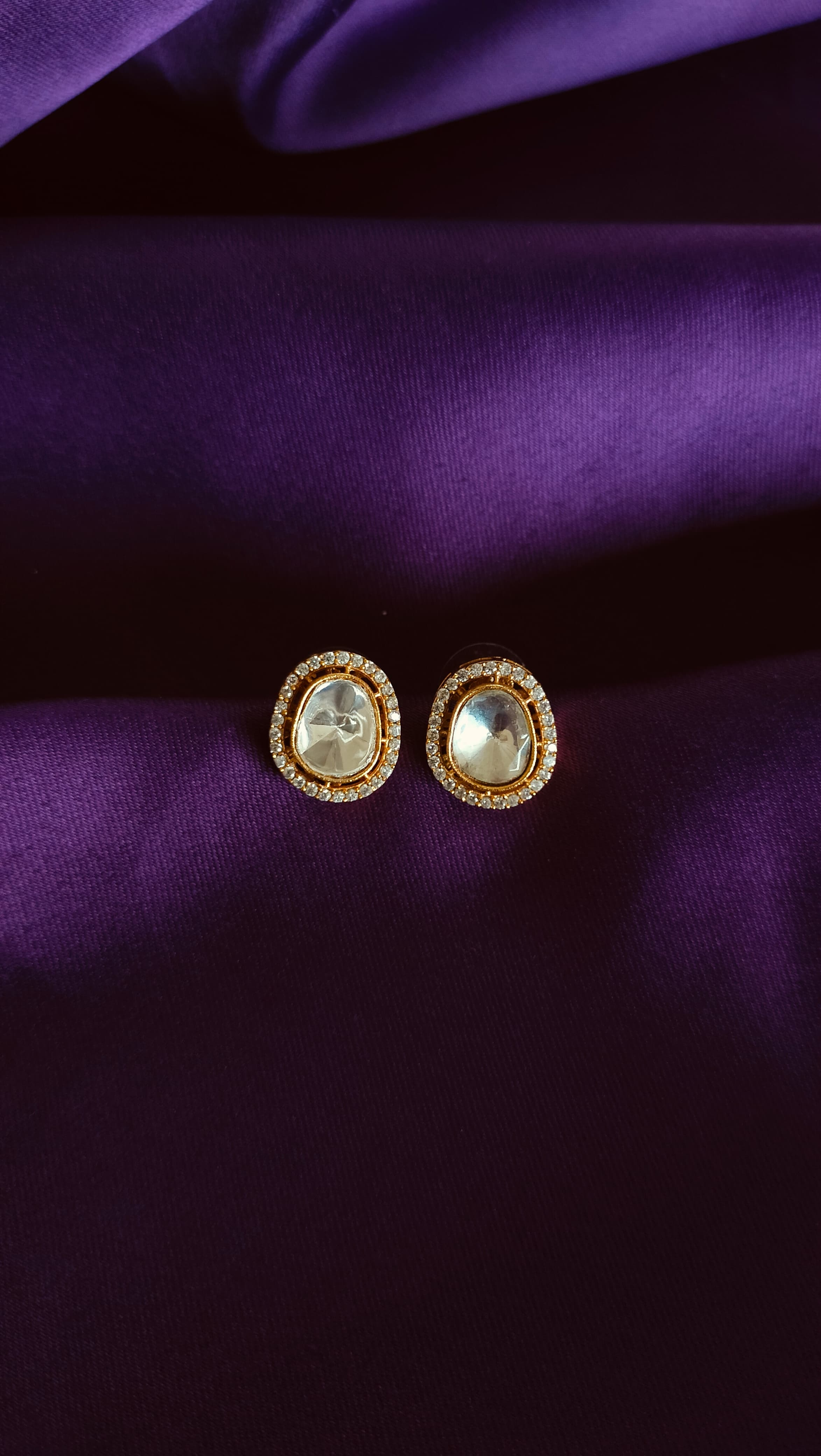 Gold Oval Polki Pavé Halo Stud Earrings pair flat lay on purple fabric