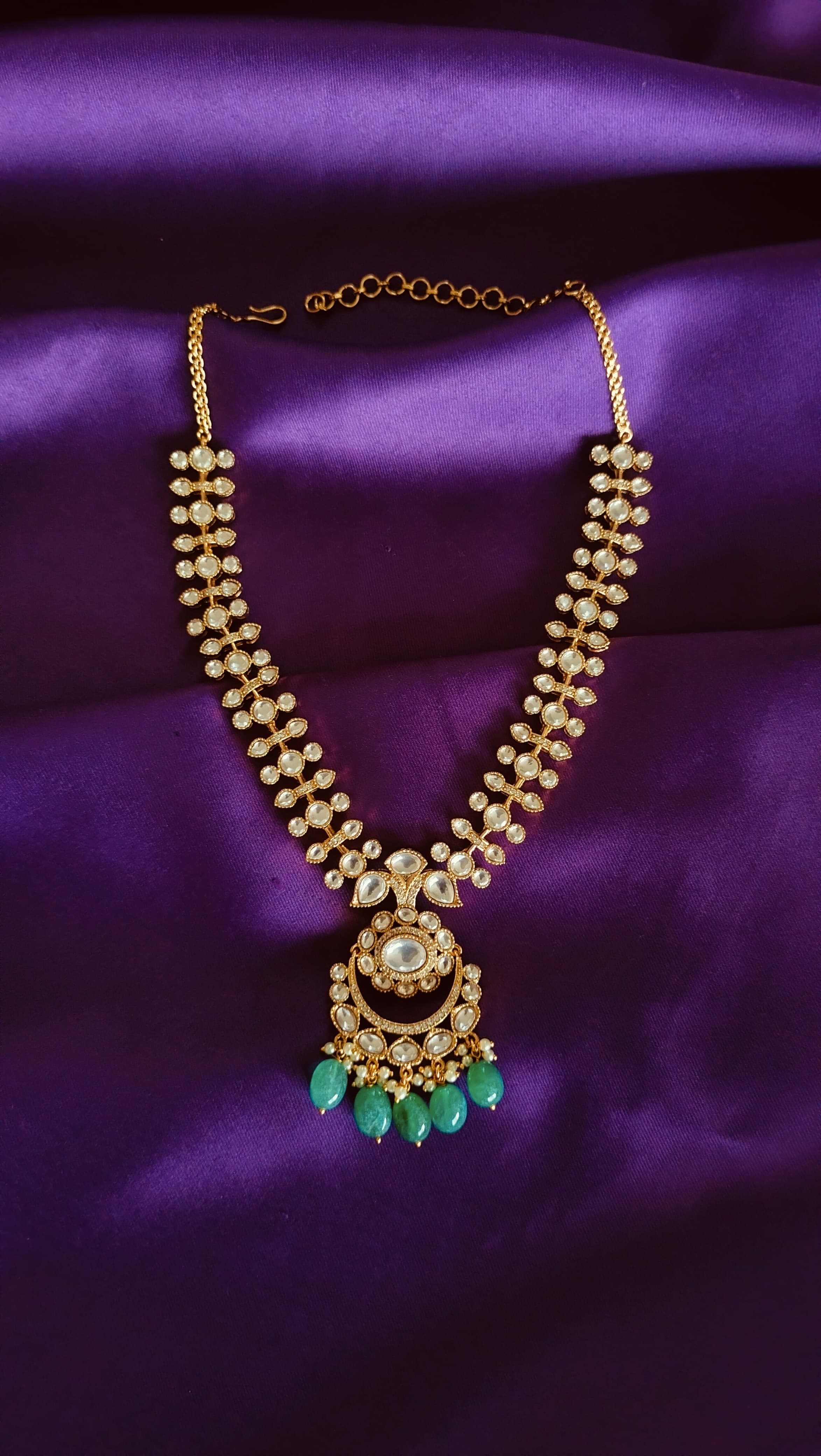 Gold Kundan Polki Graduated Necklace full length flat lay on purple fabric with chain extender